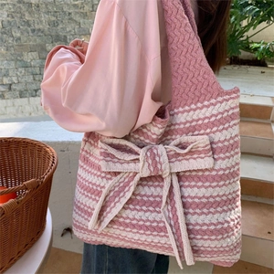 Knitted tote bag with pink and white wavy stripes and a large decorative bow detail