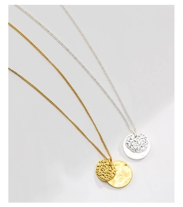 Detail of gold and silver necklaces featuring irregular hammered round disc pendants