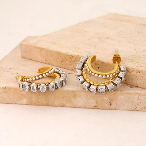Close-up of gold plated C-hoop earrings with parallel rows of oval zircons and small pearls