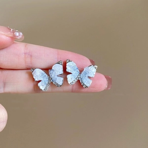 Vue détaillée des boucles d'oreilles papillon avec nacre bleue et zircons brillants