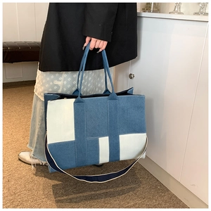 Detail of large capacity denim tote bag with blue and beige color block stitching