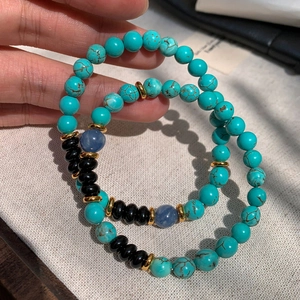 Blue turquoise and black agate beaded bracelet with gold spacers on textured background