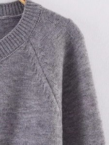 Close-up of the grey knitted cardigan showing soft texture and raglan sleeve shoulder seam