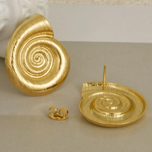 Macro view showing brushed gold finish and spiral seashell texture on stainless steel studs