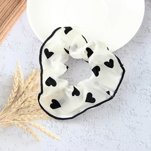 Detailed view of white chiffon scrunchie with black heart patterns and contrast piping