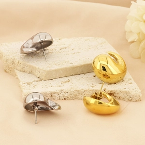 Polished teardrop earrings in gold and silver finish on a minimalist stone display