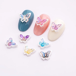 Macro detail of gradient crystal butterfly nail charms with colorful metal frames