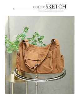 Detail of earthy brown canvas messenger bag with pockets on a glass metal table