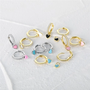 Macro detail of heart enamel charms with pave set zircon on gold and silver hoops