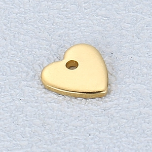 Macro view of a gold heart pendant charm with a smooth surface and precise hole