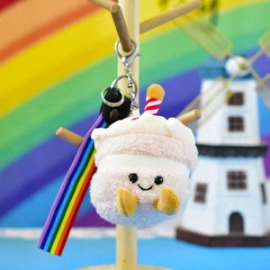 Close-up of a cute plush cake keychain featuring a smiling face and colorful rainbow strap.