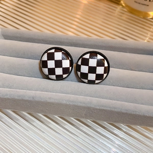 Classic round checkerboard stud earrings with black and white leather texture on gray stand