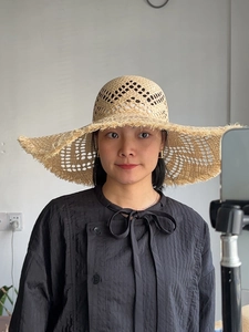 Detail of hand-woven raffia sun hat featuring hollow patterns and frayed edge design