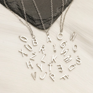 Silver stainless steel 26-letter pendant necklace set on a textured fabric and rock