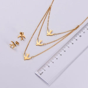 Detailed view of triple-layer gold flying bird necklace set with matching stud earrings