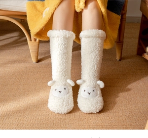 Detail of plush white floor socks with a cute sheep design and soft fuzzy texture