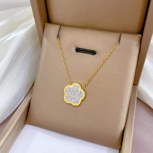Detail of a gold floral pendant necklace with sparkling crystals in a beige jewelry box
