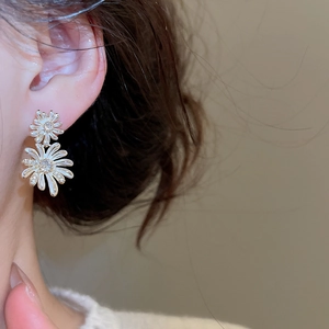 Close-up of double-layer daisy drop earrings with white enamel and sparkling zircon pavé