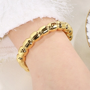 Detailed view of an 18k gold-plated segmented bamboo style bracelet on a female wrist