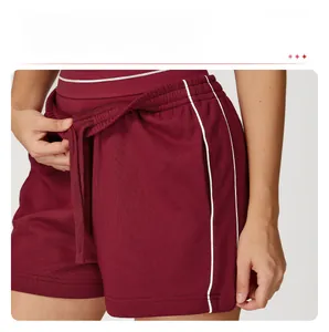 Dettaglio dei pantaloncini sportivi bordeaux con strisce laterali bianche e coulisse