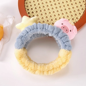 Détail du bandeau en peluche bleu et jaune avec adorable étoile et figurine de cochon