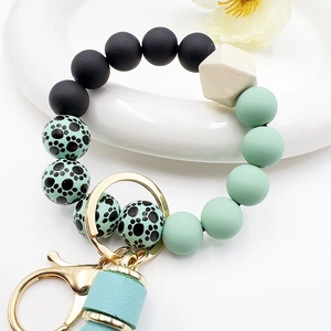 Detail of beaded keychain with silicone beads, wooden bead, gold clasp and mint tassel