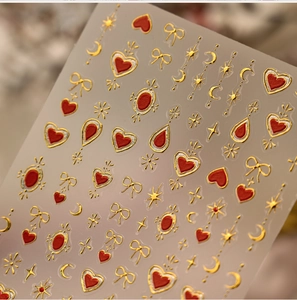 Macro shot of 3D embossed red heart and gold bow nail art stickers with metallic texture