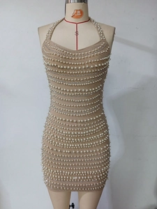 Detail view of beige halter dress featuring dense rows of white pearls and rhinestones