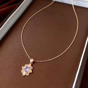 Detailed macro of 14k gold plated flower pendant featuring a central purple gemstone