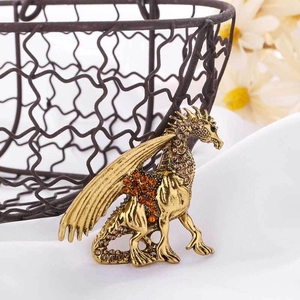 Macro detail of a vintage gold dragon brooch with amber rhinestones on white silk