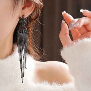 Gros plan de boucles d'oreilles fleurs noires à pompons avec strass portées par un mannequin