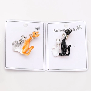Detail of enamel cat brooches with rhinestone bows on white fashion jewelry card