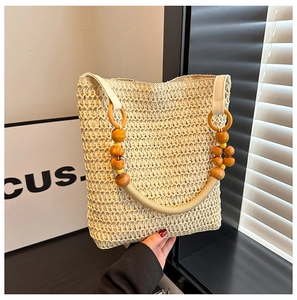 Detail of beige straw handbag featuring unique wooden bead handles in a rustic style