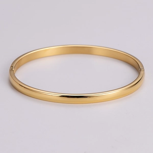 Detailed view of golden polished metal bangle featuring a secure hinge closure mechanism