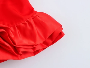 Macro view of red silk satin fabric texture and ruffled hemline of the layered skirt