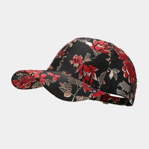 Close-up of black baseball cap with intricate red and gold floral embroidery patterns
