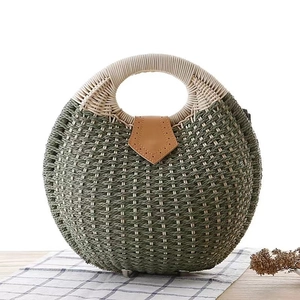 Army green woven straw handbag with white circular handles and brown leather flap detail