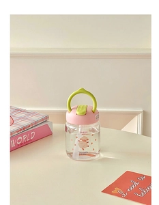 Close-up of portable glass water bottle with sheep pattern, pink lid, and green handle