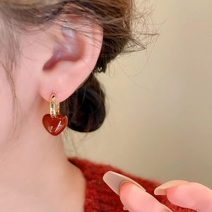 Détail de boucles d'oreilles vintage avec pendentif cœur rouge portées par un mannequin