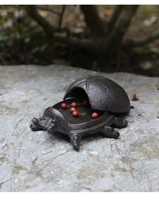 Close-up of vintage cast iron turtle key box with a textured metal finish on stone