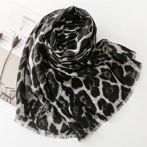Detail of leopard print cotton scarf with soft fringe edges on a minimalist background