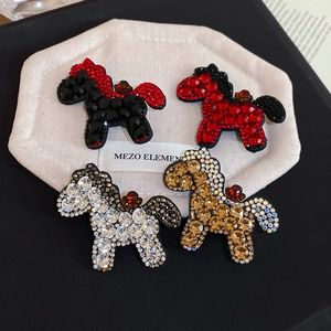 Close-up of four horse-shaped hair clips encrusted with vibrant rhinestones on white velvet