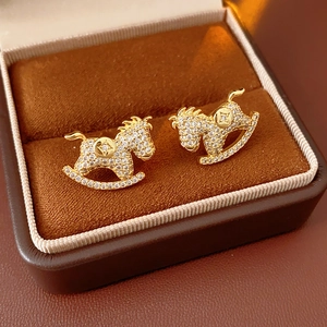 Macro shot of gold rocking horse stud earrings with zircon inlay in a velvet box
