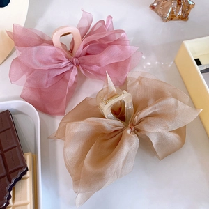 Close-up of elegant oversized mesh ribbon hair claws in soft pink and champagne tones