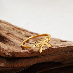 Detailed view of an 18K gold bow ring displayed on a rustic wood surface for women