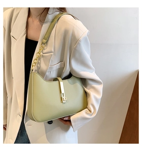 Detail of pistachio green leather underarm bag with gold metal buckle and chain strap