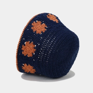 Detailed close-up of crochet floral pattern on dark blue knit bucket hat with orange edges