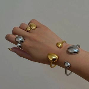Close-up of liquid metal style gold and silver plated teardrop open bracelets and rings