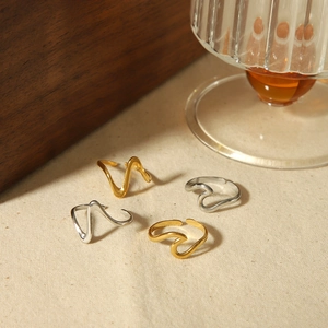 Minimalist wavy open rings in gold and silver finish on a stylish lifestyle background