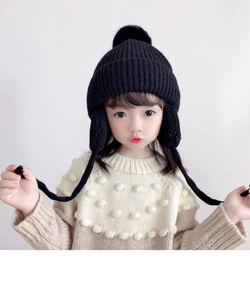 Detailed view of the soft black knit hat with earflaps and a faux fur pompom for kids